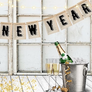 May include: A festive New Year's Eve scene with a banner reading "HAPPY NEW YEAR" against a white window backdrop. Includes champagne, party hats, and a bucket of ice. Gold confetti adds sparkle to the celebration.