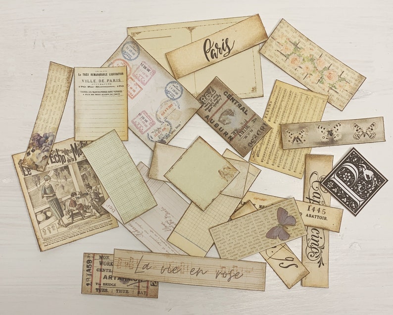 Puede incluir: Una colecci&oacute;n de ef&iacute;meras vintage, incluyendo recortes de papel, boletos y postales, con texto e im&aacute;genes francesas. Las ef&iacute;meras est&aacute;n en varios tonos de marr&oacute;n y crema, algunas con dise&ntilde;os florales. El texto incluye "Par&iacute;s", "La vie en rose" y "Ville de Paris".
