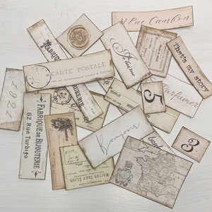 Puede incluir: Una colecci&oacute;n de etiquetas de papel de estilo vintage con varios textos y n&uacute;meros. Las etiquetas son en tonos de marr&oacute;n y crema con letras negras. Algunos de los textos incluyen "Carte Postale", "Fabrique de Bijouterie", "That's my story", y "Parfumer".