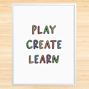 May include: A white framed print with the words "PLAY CREATE LEARN" in colorful, outlined letters.