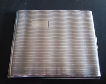 May include: A silver cigarette case with a ribbed design and a small engraved inscription that reads "J.S.H."
