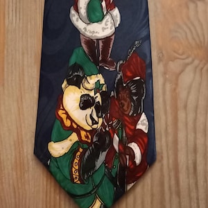Könnte beinhalten: Marineblaue Krawatte mit einem sich wiederholenden Muster von Cartoon-Bären, die als Weihnachtsmänner verkleidet sind. Die Bären tragen rote Mäntel mit weißer Bordüre, grüne Handschuhe und Weihnachtsmützen. Auf einer Holzoberfläche.
