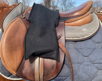 May include: A brown leather saddle with a black fleece saddle pad on a horse. The saddle has a brown leather flap and a silver buckle.