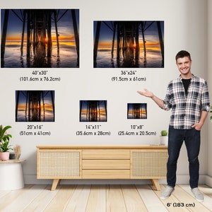 May include: A comparison of different sizes of a photograph of a pier at sunset. The photograph shows a wooden pier extending into the water with the sun setting in the background. The pier is reflected in the water. The image shows the different sizes of the photograph available for purchase.