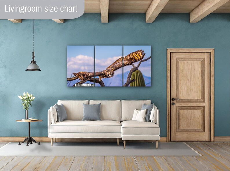 May include: A triptych canvas print featuring a detailed image of an owl perched on a tree branch against a blue sky. The artwork is displayed above a white sofa in a living room setting. The print size is 36x72 inches / 91x183 cm.