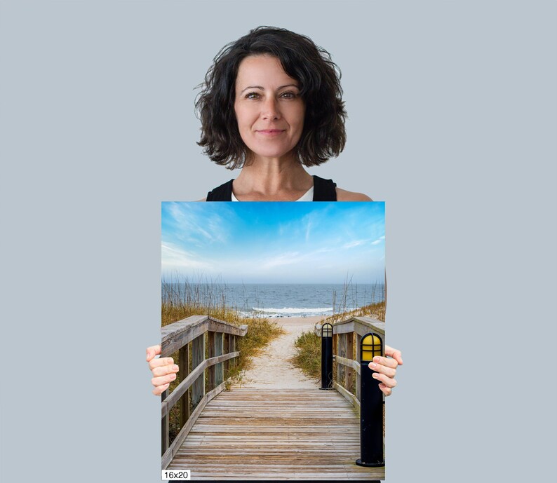 May include: A wooden walkway leads to a sandy beach with blue water and a clear sky. The walkway is lined with tall grass on either side. The image is labelled "16x20".