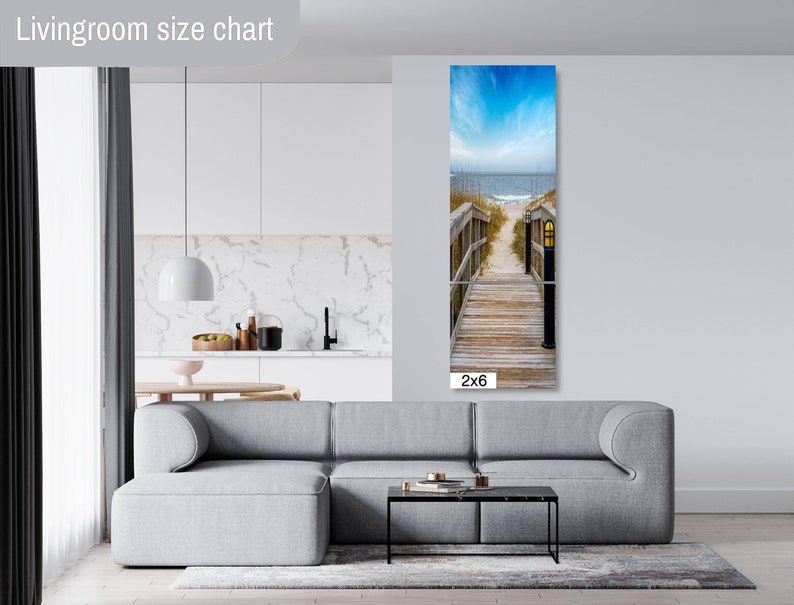 May include: A photograph of a wooden walkway leading to the beach. The walkway is lined with wooden railings and has a lamp post at the end. The beach is in the background and the sky is blue with white clouds. The image is labelled "2x6".