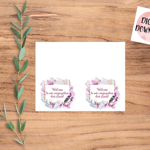 Puede incluir: Dos carteles de bienvenida imprimibles con un diseño floral con flores de magnolia rosas y un pájaro azul. El texto en los carteles dice "Bienvenido a nuestra congregación querido amigo."