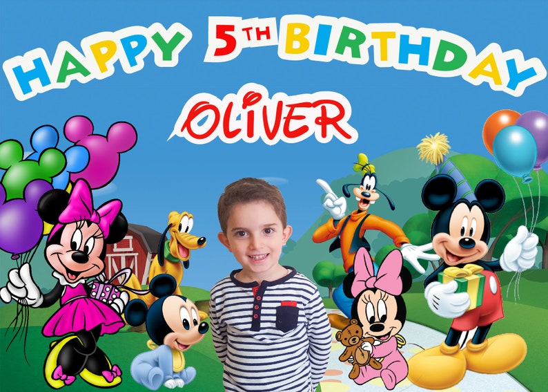May include: A birthday banner with the words "Happy 5th Birthday Oliver" in colorful letters. The banner features Mickey Mouse, Minnie Mouse, Goofy, and Pluto. There are also balloons in the background.