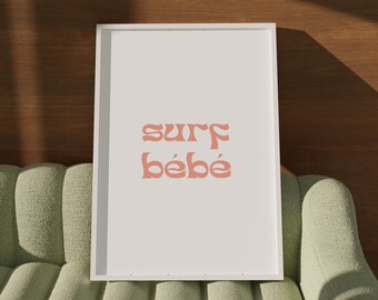 May include: A white framed print with the text "surf bébé" in pink on a green sofa.