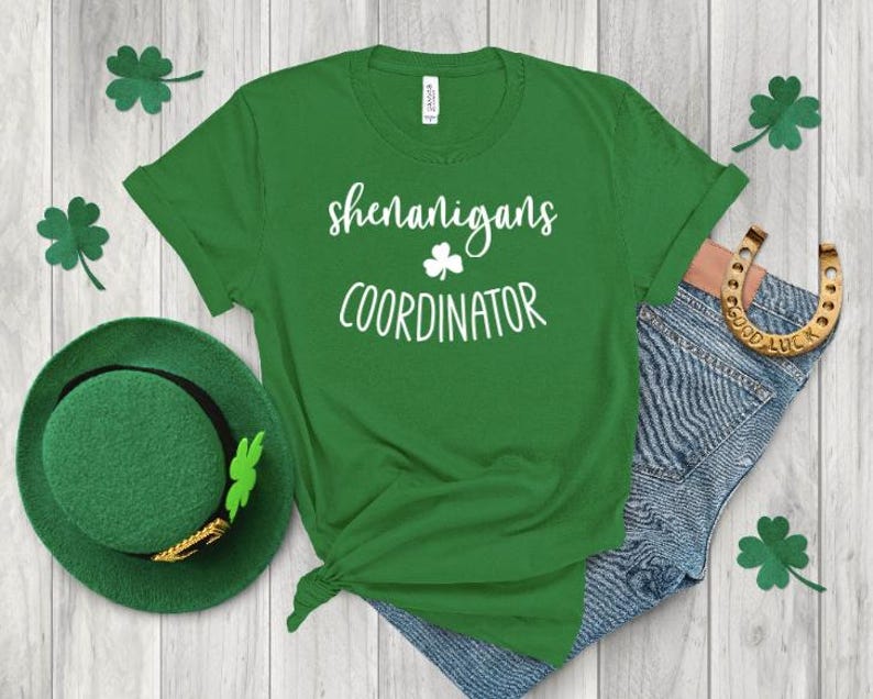 Peut inclure: T-shirt vert avec un texte blanc qui dit "Shenanigans Coordinator" et un graphique de tr&egrave;fle.