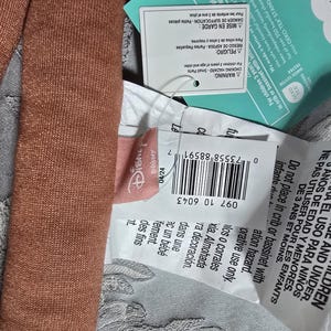 May include: Close-up of a brown plush toy with attached tags. The tags include the Disney logo, a barcode, and warnings in multiple languages about choking hazards for children.