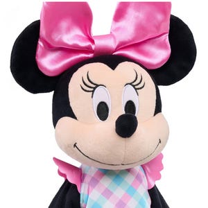 May include: A plush Minnie Mouse doll with black ears and a large pink satin bow. The doll has a light pink face, black eyes, and a black nose. She wears a dress with a pastel plaid pattern and pink ruffled sleeves.