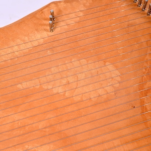 May include: A wooden harp with a light brown finish and silver tuning pegs. The harp has a unique pattern in the wood grain.