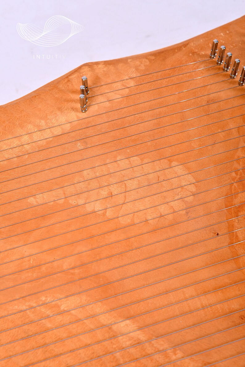 May include: A wooden harp with a light brown finish and silver tuning pegs. The harp has a unique pattern in the wood grain.