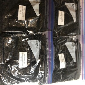 Puede incluir: Cuatro bolsas de plástico transparentes con cierre de cremallera, cada una contiene briquetas de carbón vegetal negro. Las bolsas están etiquetadas con "Arboreal Attitudes Hardwood Organic Charcoal Qty: 2 QT" y "Ziploc".