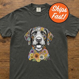 May include: Dark gray t-shirt featuring a detailed illustration of a dog with colorful floral patterns on its head and neck. The shirt has a crew neck and short sleeves. The text "Ships Fast!" is in a circle in the upper right corner.
