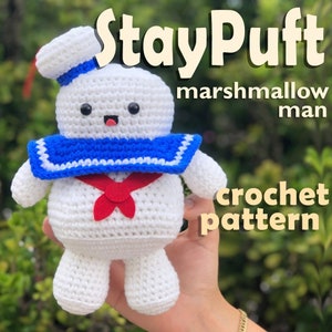 May include: White crocheted Stay Puft marshmallow man with a blue and white sailor collar and a red bow tie. Crochet pattern.