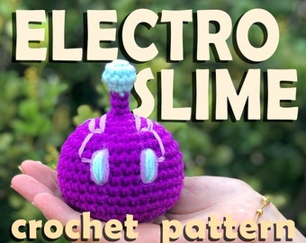 Pode incluir: Padrão de crochê para um Electro Slime, uma criatura de crochê roxa com olhos azuis e uma parte superior azul claro. A criatura está sendo segurada em uma mão.