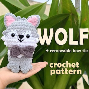 Puede incluir: Un lobo tejido a mano con detalles grises, blancos y rosas, con una pajarita extraíble. La imagen incluye la palabra "WOLF", el texto "+ removable bow tie" y "crochet pattern".