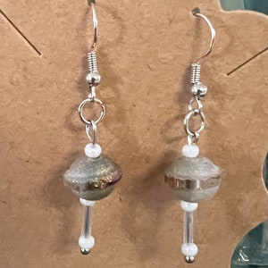 May include: A pair of silver earrings with a green and gold bead and a white bead on each earring.