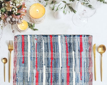 May include: A woven placemat with red, white, and blue stripes. The placemat is made of recycled denim and is perfect for adding a touch of rustic charm to your table setting.
