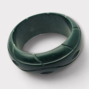 May include: A dark green carved bangle bracelet with a geometric design.