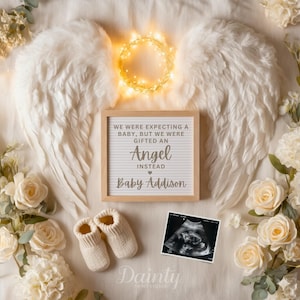 Può includere: Un toccante allestimento commemorativo con ali d'angelo bianche, un alone luminoso e un messaggio incorniciato: "WE WERE EXPECTING A BABY, BUT WE WERE GIFTED AN Angel INSTEAD Baby Addison." Include scarpine e un'ecografia.