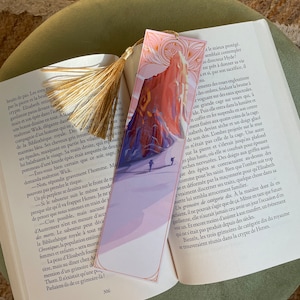 Könnte beinhalten: Ein rosa-blaues Lesezeichen mit einem goldenen Quasten. Das Lesezeichen zeigt eine Bergkette mit zwei Personen, die den Berg hinaufwandern. Der Text auf dem Lesezeichen lautet "a le mieux protégé. semblait contempler le directeur Hyde? est prêt à donner sa vie et si, par son sacrifice, il"