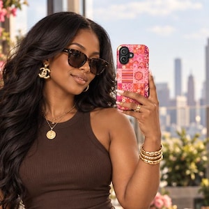 May include: A dark brown ribbed tank top and matching high-waisted tailored shorts with pleats. The outfit is accessorized with gold jewelry, a pink crocodile-embossed handbag, and dark sunglasses, while holding a pink patterned smartphone.
