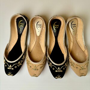 May include: Four pairs of gold and black embroidered flat shoes. The shoes have a pointed toe and a small heel. The shoes are decorated with gold embroidery and have a black velvet lining.