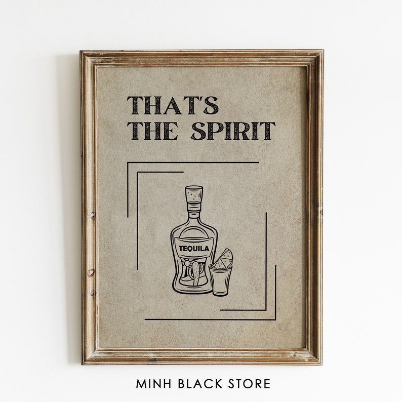 May include: A framed print with the text "That's the spirit" and a black and white illustration of a tequila bottle and shot glass. The print has a brown background and a wooden frame.