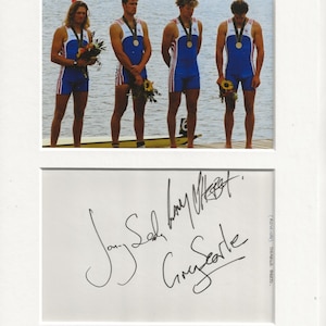Puede incluir: Una fotografía en blanco y negro de cuatro hombres con uniformes de remo de pie en un muelle. Sostienen ramos de flores y tienen medallas alrededor del cuello. La foto está firmada por los hombres, con los nombres "Jon Searle", "Jonny Searle", "Greg Searle" y "James Cracknell".