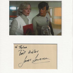 Può includere: Una fotografia in bianco e nero firmata da James D'Arcy, un attore noto per il suo ruolo nella serie televisiva "Cloud Atlas". La foto mostra D'Arcy con una donna, e l'iscrizione dice "To Thelma, Best Wishes, James D'Arcy".