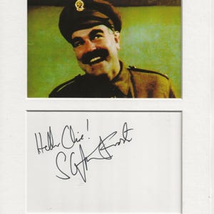 May include: A black and white photo of a man in a military uniform smiling. The man is wearing a hat with a badge on it. The photo is signed "Hello Chris!" with the name "Stephen Frost" underneath.
