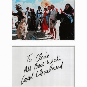 Może przedstawiać: Oprawione zdjęcie przedstawiające grupę osób w historycznych strojach, prawdopodobnie kadr z filmu. Obraz zawiera odręczną wiadomość: "To Cleve, All Best Wish, Carol Cleveland."