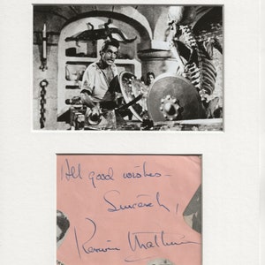 Peut inclure: Photographie en noir et blanc d'un homme dans une scène de film, tenant une épée et un bouclier. L'homme porte une tunique et a une barbe. La photo est signée par l'acteur, "All good wishes - Sincerely,  Peter O'Toole".
