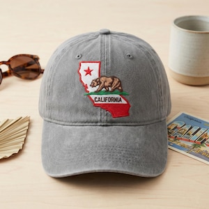 Peut inclure: Casquette de baseball grise avec un écusson brodé de la Californie, représentant un ours et une étoile. Le mot "CALIFORNIA" est brodé en dessous. La casquette a une visière incurvée et une conception classique à six panneaux.
