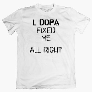 Peut inclure: T-shirt blanc avec du texte noir qui dit "L DOPA FIXED ME ALL RIGHT"