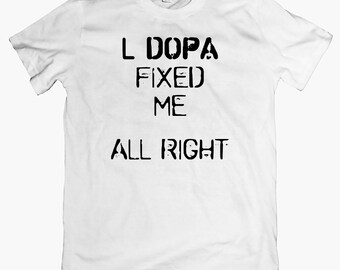 May include: White t-shirt with black text that reads "L DOPA FIXED ME ALL RIGHT"