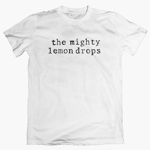Può includere: T-shirt bianco con la scritta nera "the mighty lemon drops" stampata in un carattere di macchina da scrivere. La maglietta ha maniche corte e girocollo. Abbigliamento casual.