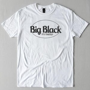 Könnte beinhalten: Weißes T-Shirt mit dem schwarzen Schriftzug "Big Black" in einem ovalen Design. Darunter steht der Satz "It's Toasted" in Schwarz. Das T-Shirt hat einen Rundhalsausschnitt und kurze Ärmel, perfekt für den Alltag.
