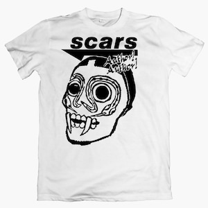 May include: White t-shirt featuring a black graphic of a stylized skull with large eyes and fangs. The word "scars" is above the skull, with "Author! Author!" below. The design is bold and graphic.