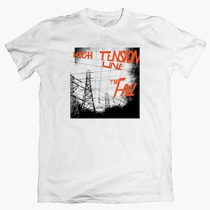 Könnte beinhalten: Weißes T-Shirt mit einem orangefarbenen Grafikdesign. Das Design zeigt die Wörter "HIGH TENSION LINE" und "THE FALL" sowie eine schwarze Silhouette von Strommasten und Hochspannungsleitungen.