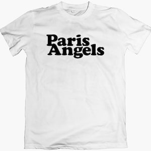 Może przedstawiać: Biała koszulka z czarnym nadrukiem "Paris Angels" z przodu.