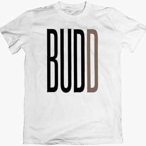 Puede incluir: Camiseta blanca con la palabra "BUDD" impresa en letras negras y marrones.