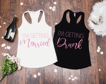 May include: Two white tank tops with black text. The top on the left says "I'm getting married" in pink script. The top on the right says "I'm getting drunk" in pink script.