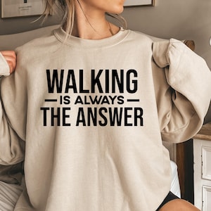May include: A beige sweatshirt with the text "WALKING IS ALWAYS THE ANSWER" printed in black.