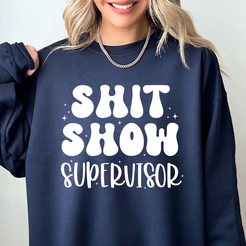 a woman wearing a sweatshirt that says shit show supervisor