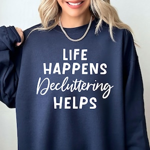 May include: Navy blue sweatshirt with white text that reads "Life Happens Decluttering Helps".
